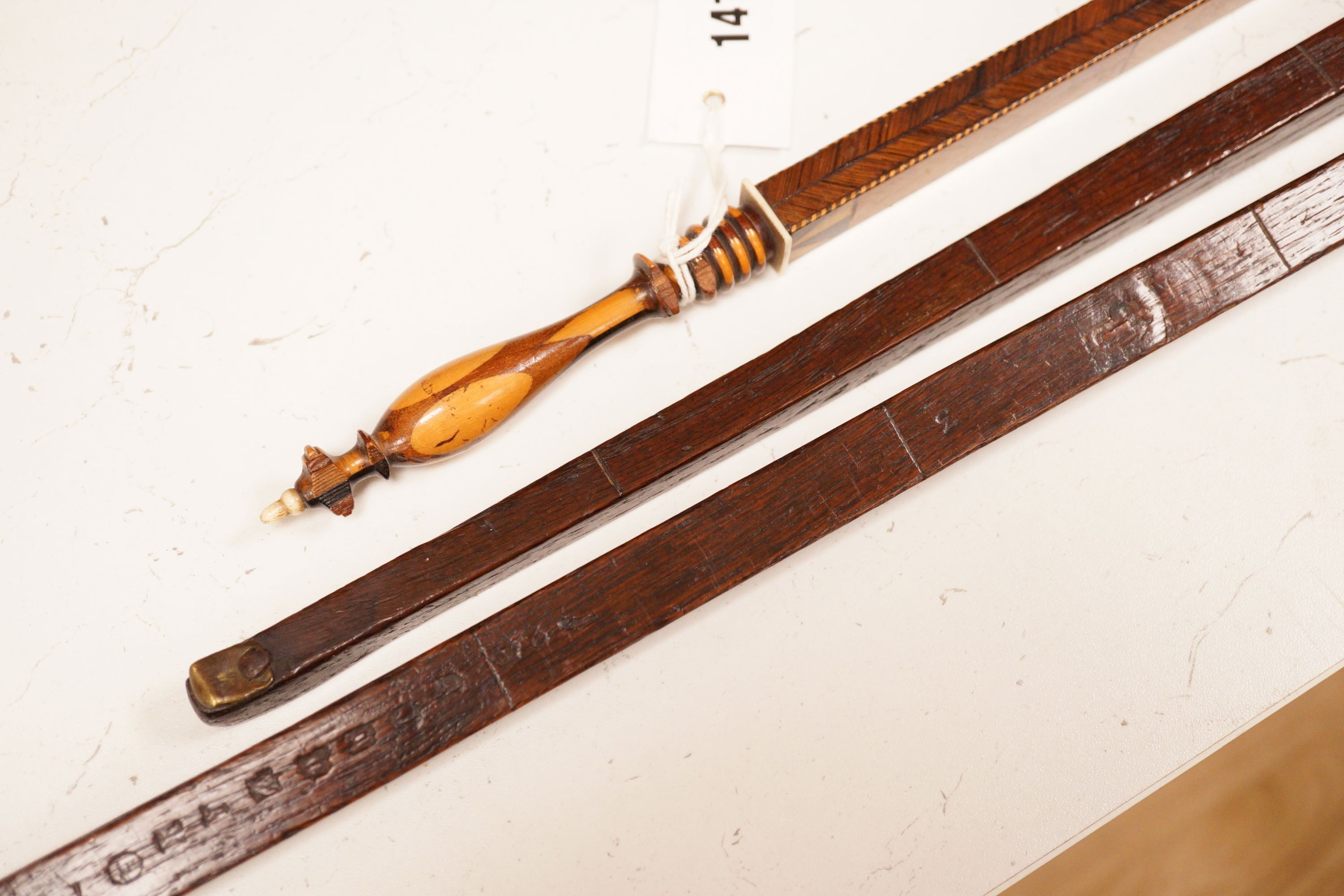 Three assorted 19th century treen measuring sticks to include a kingwood feather banded and marquetry inlaid measuring stick with stickware finial